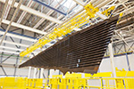 Ein dreieckiges Bauteil mit Lamellen für ein Flugzeug in einer Montagehalle. Foto: Airbus