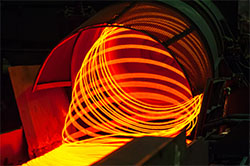 Glühende Edelstahlrolle kommt aus der Produktion. Foto: Shutterstock/SUSTEC