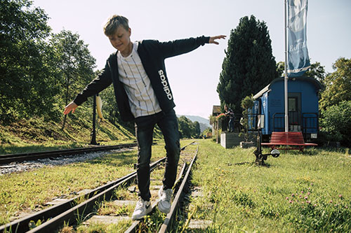 Ein Junge balanciert über Bahngleise. Foto: Slow Trips - Bernhard Bergmann