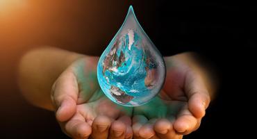Zwei Hände fangen einen Wassertropfen, der so aussieht wie die Weltkugel. Foto: iStock